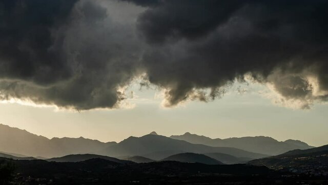 Dramatic 4K uhd cloudy sky sunset timelapse - One big black cloud on mountains be crossed from the sun with his light rays