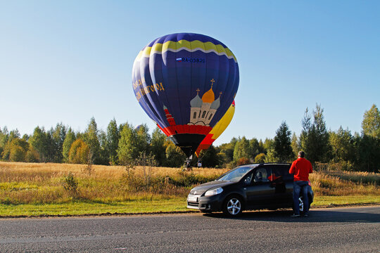 Pereslavl-Zalessky, Russia - September 23, 2017: Man near the car watching as two hot air balloons land on the field at the festival of aeronautics in Pereslavl-Zalessky