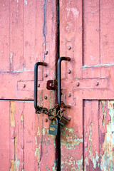 Old grungy wooden door with rusty chain and two padlocks