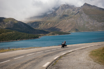 Trail motorcycle rider leading towards a curve in alpine road of Mont Cenis, Italy