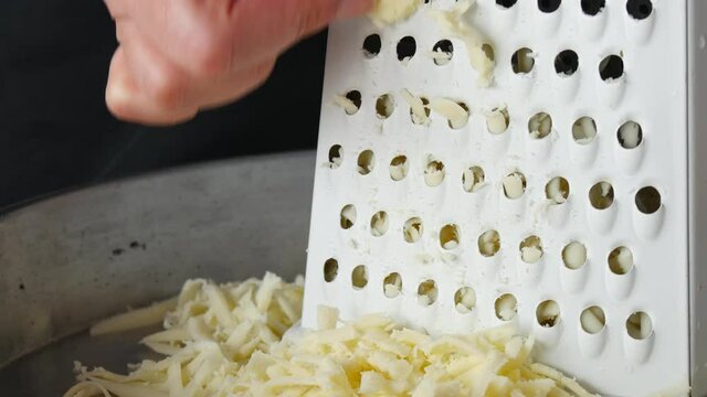 Chef grating cheese for pizza, close up