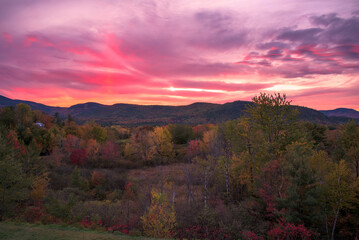 Stunning sunset over forested mountains during the peak of autumn colour season. North Conway, NH, USA.