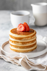 Suck of classic american pancakes with strawberry  and sirop . black coffee cup and milk on the white table. Copy space