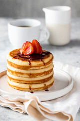 Stack of classic american pancakes with strawberry  and sirop . black coffee cup and milk on the white table. Copy space