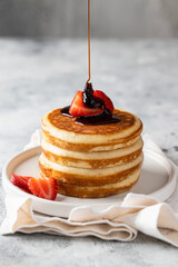 Maple syrup pouring pancakes with strawberry  and coffee cup on the table. Classic American breakfast concept