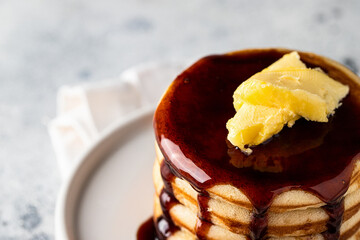 Stack of pancakes with butter and caramel on light concrete background. Classic American breakfast