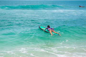 Sexy slim girl riding on surf board in the ocean. Healthy active lifestyle in summer vocation.