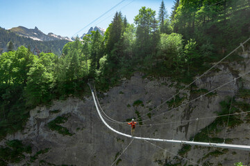 Woman climbing via ferrata in switzerland while crossing bridge