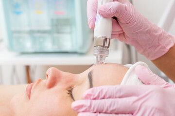 Beauty salon. The cosmetologist in medical gloves doing a water peeling procedure on the client's...