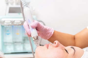 Beauty salon. The cosmetologist makes a water peeling procedure for the client in the chin area....
