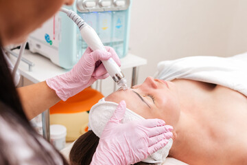 Beauty salon. The cosmetologist makes a aqua peeling procedure for the client. View from the...