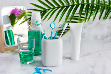 Set of dental hygiene products on white marble table.