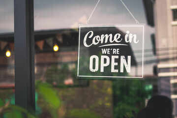 Come in we're open, vintage black retro sign in glass door storefront