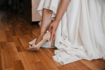 bride in a white dress wears a Shoe on the wedding day
