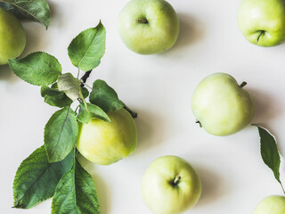 Composition of green apples and leaves on white background. Wallpaper of fruits.Top view, flat lay.