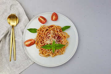 Pasta with tomatoes, cheese and basil on a light background. Top view, copy space 