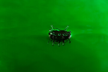 Drop green color falling and forming waves ripples