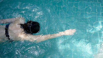 The top view of women is swimming in the swimming pool 