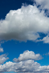 Beautiful blue sky background at daylight with white cumulus clouds. Vertical orientation