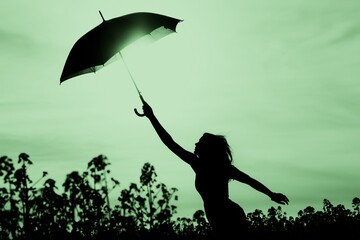 Unplugged free silhouette woman with umbrella up to green sky. Nature girl at windy rainy day has adventure wanderlust. Wonderful scene of imagination power and departure to new horizons in youth