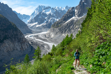 Fototapeta na wymiar Trail runner woman running with scenic view Mer du Glace Glacier in Mont Blanc Mountain Ridge in Chamonix, France