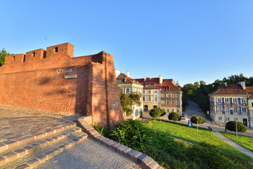 Fototapeta na wymiar The historic defensive walls of the Warsaw Barbican and burgher houses in the Old Town in the light of the rising sun.