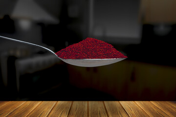 spoon full of paprika in a dark kitchen over a wood table