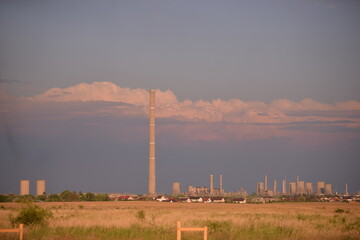 Fototapeta na wymiar oil refinery seen on the horizon on the wheat field at sunset