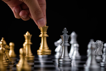 Hand holding and move golden king chess to silver chess.