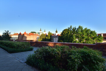 The historic defensive walls of the Warsaw Barbican and burgher houses in the Old Town in the light of the rising sun.