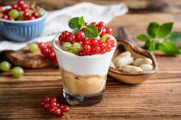Refreshing cream cheese dessert with peanut butter and sponge biscuits, topped with fresh gooseberries and red currants