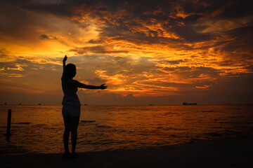 Fototapeta premium A female model silhouette controlling the movements of clouds on Ba Keo Beach