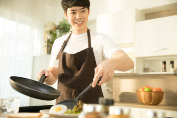 Young man is  cooking  sunny side up egg and salad for breakfast