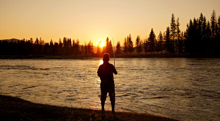 silhouette of a child fishing at sunset