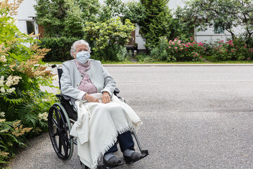 Old woman in a medical mask in a wheelchair for a walk. Coronavirus protection