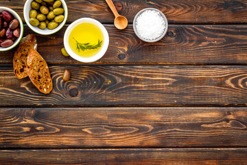 Top view of olives, olive oil, bread on wooden table top view copy space
