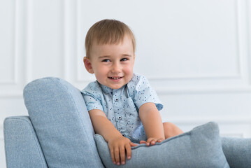 portrait of a little smiling boy child playing on the sofa in living room