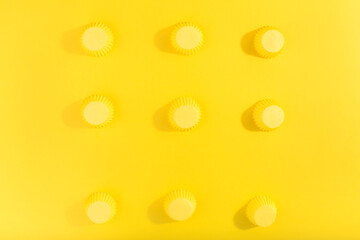 Trendy pattern made with yellow cap on bright yellow background. Minimal concept.