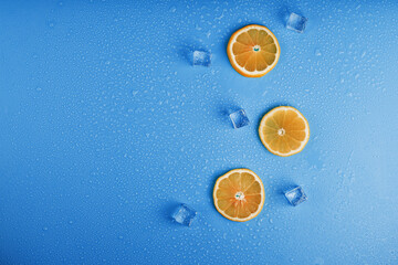 Slices of fresh orange on a blue background with ice.