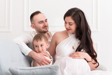 happy family in the living room married couple with small child and pregnant woman