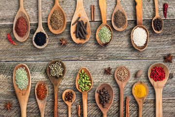 spices and herbs in old wooden spoons  on old wooden board