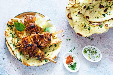 Grilled chicken kebabs (chicken skewers) with herbed garlic butter naan tortillas and Greek tzatziki sauce. Delicious street food.