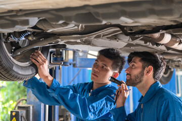 Mechanic are checking or inspecting car suspension with car lifting in car garage. Mechanic checking tire with car lifting.