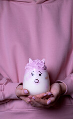 Piggy whipped milk in woman hands against the pink hoodie
