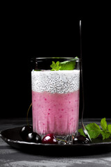 Pudding with chia seeds and mashed cherry on the grey table. Layered dessert