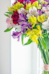 Alstroemeria bouquet of flowers in a vase by the window. Beautiful bouquet of colorful flowers in the apartment by the window.