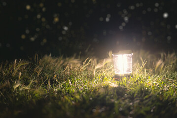 Tourist flashlight in the grass at the night background.