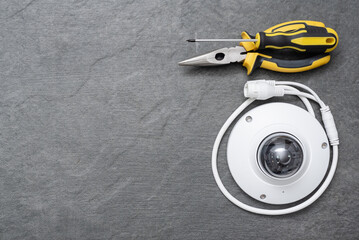 Security camera, pliers and screwdriver on the dark flat lay background with copy space.
