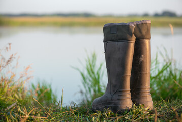 Rubber boots on the lake shore close up.