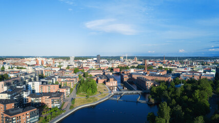 Obraz premium Aerial view of the Tampere city at sunset. Tampella building. View over Tammerkoski river in warm sunlight.